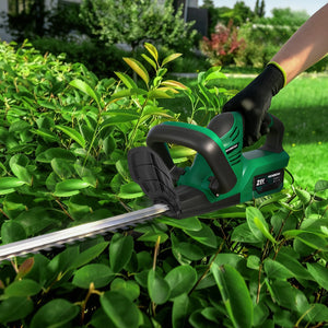 Person using a green and black hedge trimmer on a bush with a garden background